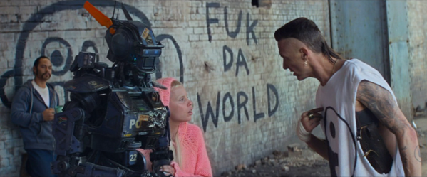 Three human figures and a robot stand outside, two of the humans talking. On the wall behind them is graffiti of a large round face and the text 'Fuk da world'.