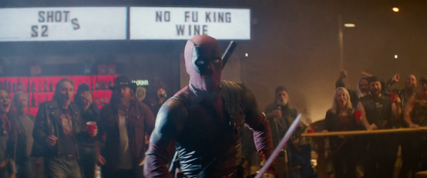 The comic character Deadpool, in full costume and holding a sword, is centre screen in a busy bar. Behind him are a crowd of cheering revellers and a sign lit up reading 'Shots' and 'No fucking wine' with the 'c' missing.