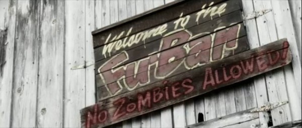 On a wooden wall is a dingy old wooden sign with hand-painted text that read, 'Welcome to the Fu-Bar. No zombies allowed!'